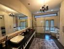 Luxurious bathroom with twin sinks, large mirror, and chandelier