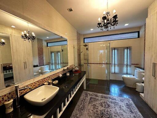 Luxurious bathroom with twin sinks, large mirror, and chandelier