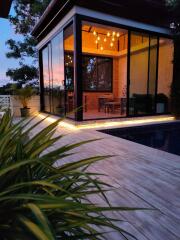 Modern glass-enclosed patio with a view of the pool and lush greenery