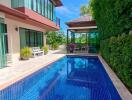 Outdoor pool area next to a modern house with green surroundings