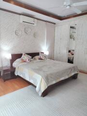 Cozy and well-lit bedroom with double bed, decorative pillows, and large wardrobe