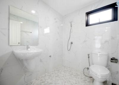 Spacious modern bathroom with wall-mounted sink, toilet, and walk-in shower