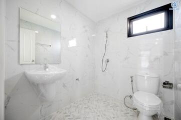 Spacious modern bathroom with wall-mounted sink, toilet, and walk-in shower