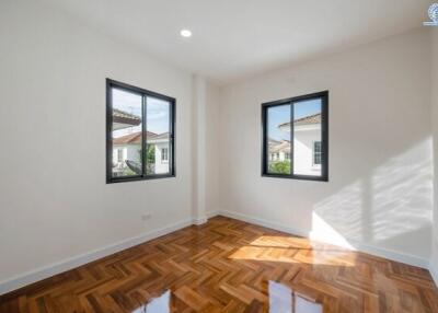 Well-lit bedroom with wooden floors and large windows