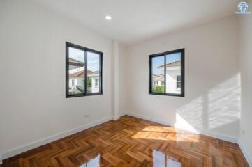 Well-lit bedroom with wooden floors and large windows