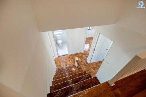 View of a staircase with wooden steps leading to a hallway and bathroom