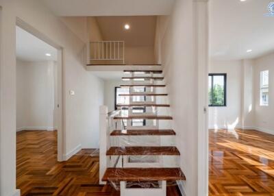 Spacious bright living area with wooden flooring and modern staircase