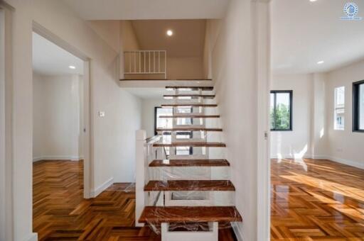 Spacious bright living area with wooden flooring and modern staircase