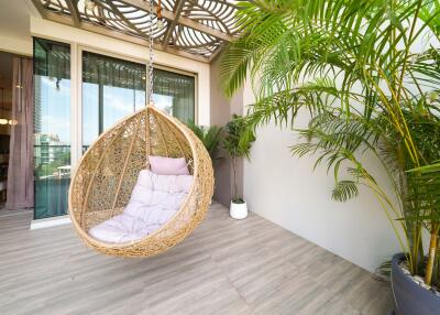 Contemporary balcony with hanging chair and greenery