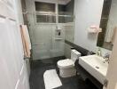 Modern bathroom with glass-enclosed shower, toilet, and sink