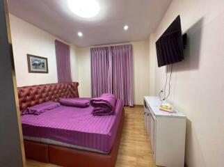 Bedroom with wall-mounted TV and purple bedding