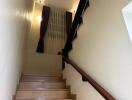 Well-lit wooden staircase with a handrail and curtains on the window