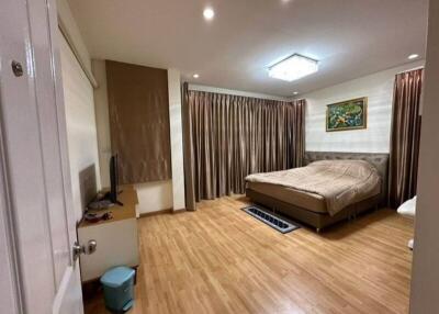Spacious bedroom with wooden flooring, large bed, and ample curtains