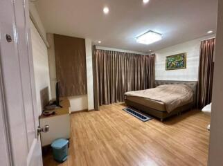 Spacious bedroom with wooden flooring, large bed, and ample curtains