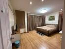 Spacious bedroom with wooden flooring, large bed, and ample curtains