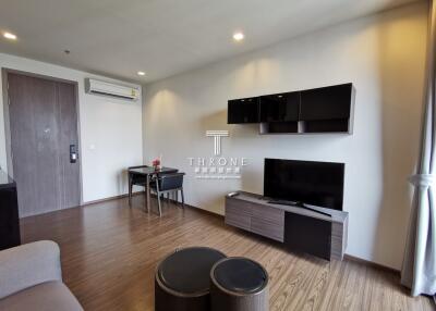Modern living room with wooden flooring, flat-screen TV, and wall-mounted shelves