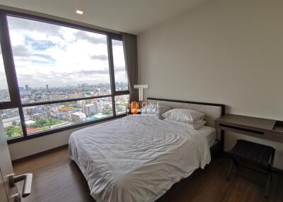 Spacious bedroom with a large window offering a stunning city view