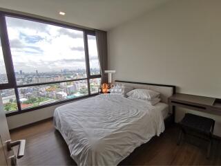 Spacious bedroom with a large window offering a stunning city view