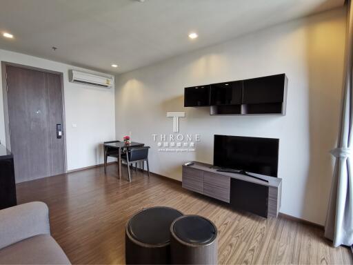 Modern living room with wooden flooring, wall-mounted TV console, and dining area with airconditioning unit on wall