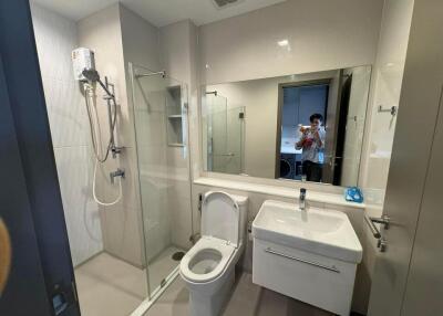 Modern bathroom with large mirror, shower, toilet, and sink
