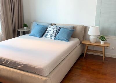 Modern bedroom with a large bed, wooden floor, bedside tables, and natural lighting