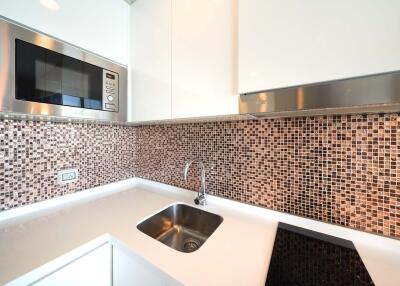 Modern kitchen with mosaic backsplash, built-in microwave, and sink