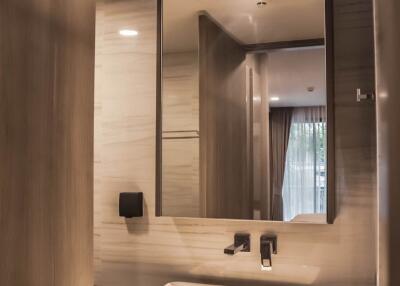Modern bathroom with wooden door, rectangular sink, large mirror, and overhead lighting