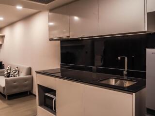 Modern kitchen with sleek cabinetry and a cozy living space in the background