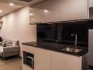 Modern kitchen with sleek cabinetry and a cozy living space in the background