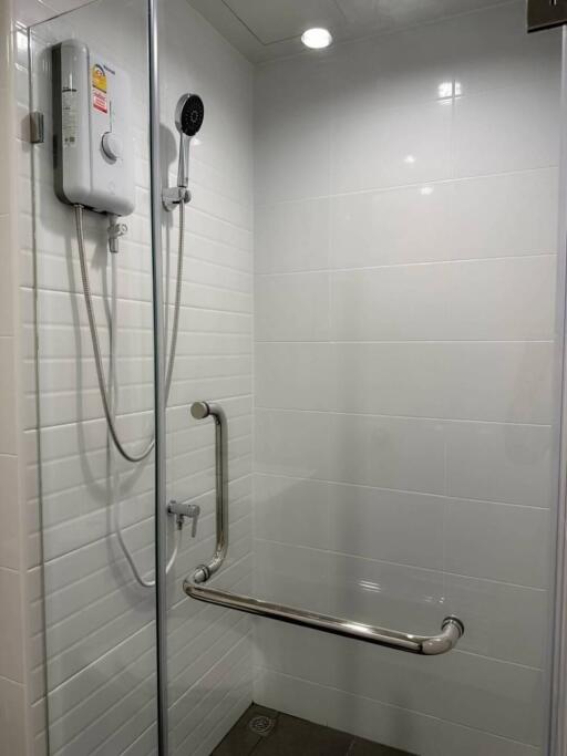 Shower area with white tiles and safety bar