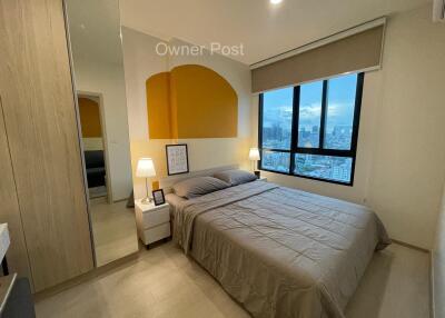 Modern bedroom with a large bed, city view, and ambient lighting
