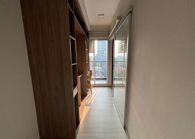 A hallway with a wooden cabinet and sliding mirror door leading to a balcony