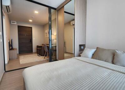 Modern bedroom with a large bed and a view into adjacent living space