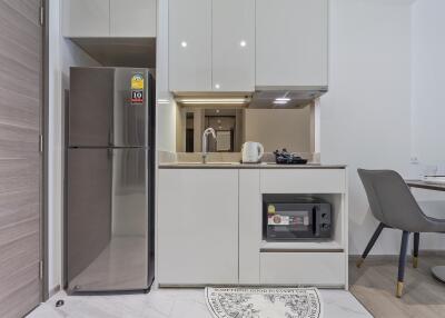 Modern compact kitchen with stainless steel refrigerator and minimalist design