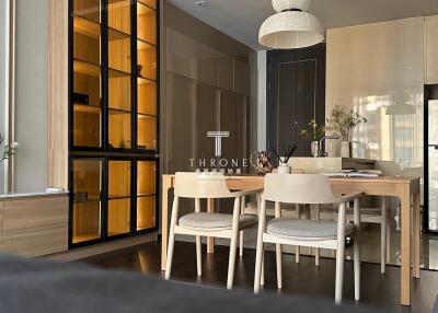 Modern dining area with wooden table and chairs, glass cabinet, and stylish lighting