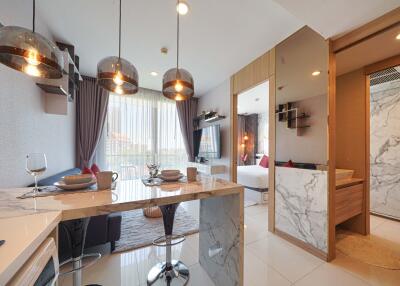 Modern open-plan living area with kitchenette, dining counter, and adjacent bedroom