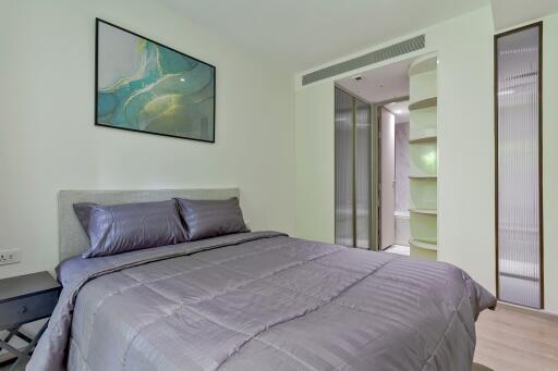 Modern bedroom with artwork, plush bedding, and an en-suite bathroom