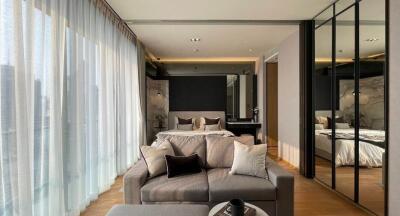 Modern living space with a well-lit sitting area and a view into the bedroom