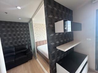 View of a bedroom with a black couch, patterned wallpaper, and a bed