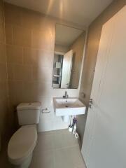 Modern bathroom with a sink, toilet, and large mirror