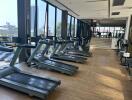 Modern gym with treadmills and large windows overlooking a cityscape