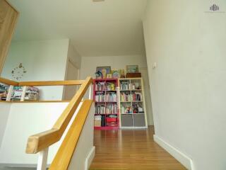 Hallway with wooden stairs and built-in bookshelf