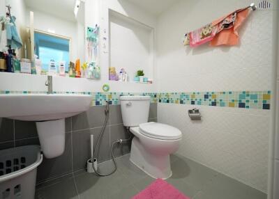 Modern bathroom with toilet, sink, and tiled walls