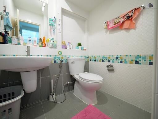 Modern bathroom with toilet, sink, and tiled walls