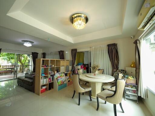 Bright dining room with modern chandelier and bookshelf