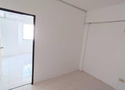 Empty white bedroom with tiled floor and open door leading to another room