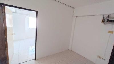 Empty white bedroom with tiled floor and open door leading to another room
