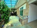 Covered outdoor patio with greenery and stone walls