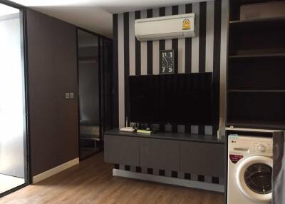 Modern living area with wall-mounted TV, air conditioner, and washing machine