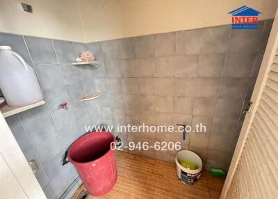 Bathroom with tiled walls and cleaning supplies